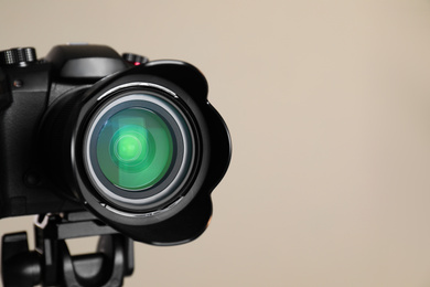 Photo of Professional video camera on beige background, closeup. Space for text