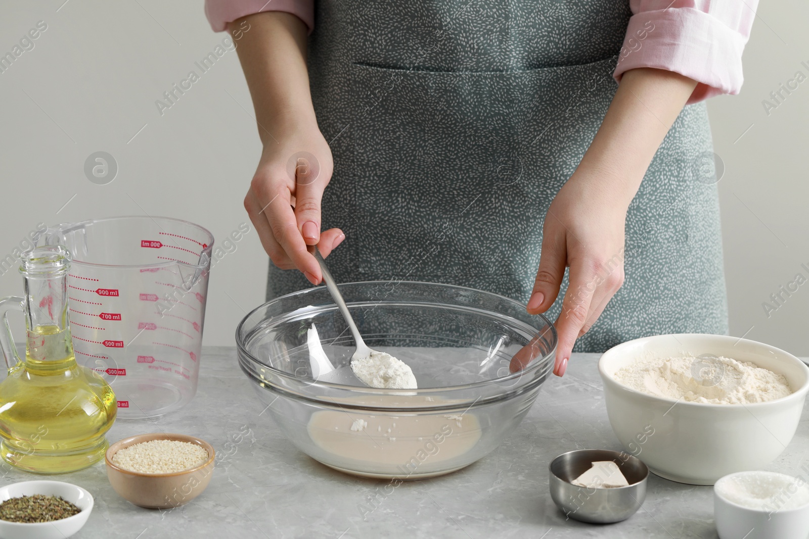 Photo of Woman making dough for traditional grissini at light grey marble table indoors, closeup