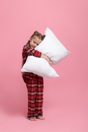 Photo of Girl in pajamas hugging pillow on pink background