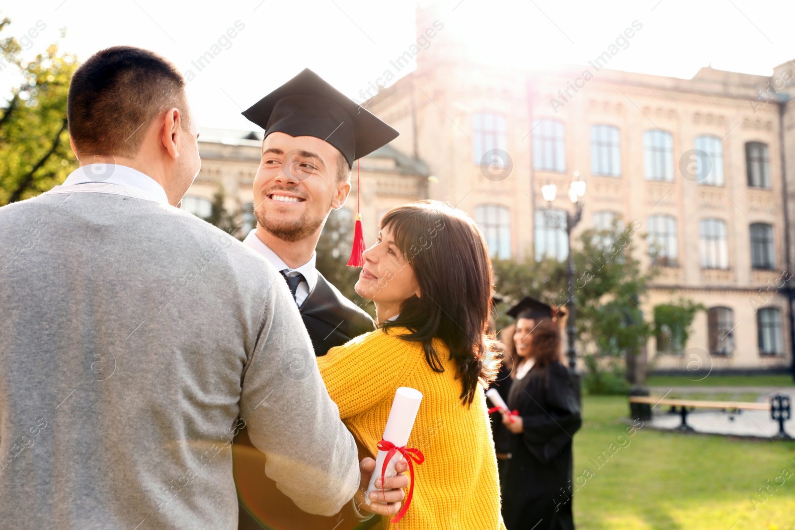 Photo of Happy student with parents after graduation ceremony outdoors