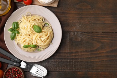 Photo of Delicious pasta with brie cheese and products served on wooden table, flat lay. Space for text