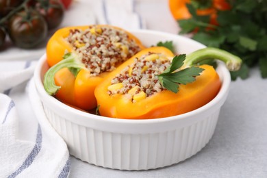 Photo of Quinoa stuffed bell pepper and parsley in bowl on light table, closeup