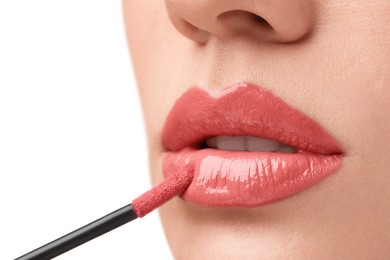Woman applying lip gloss on white background, closeup