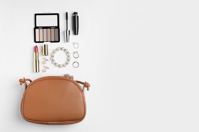 Photo of Stylish leather handbag and makeup items on white background, flat lay. Space for text