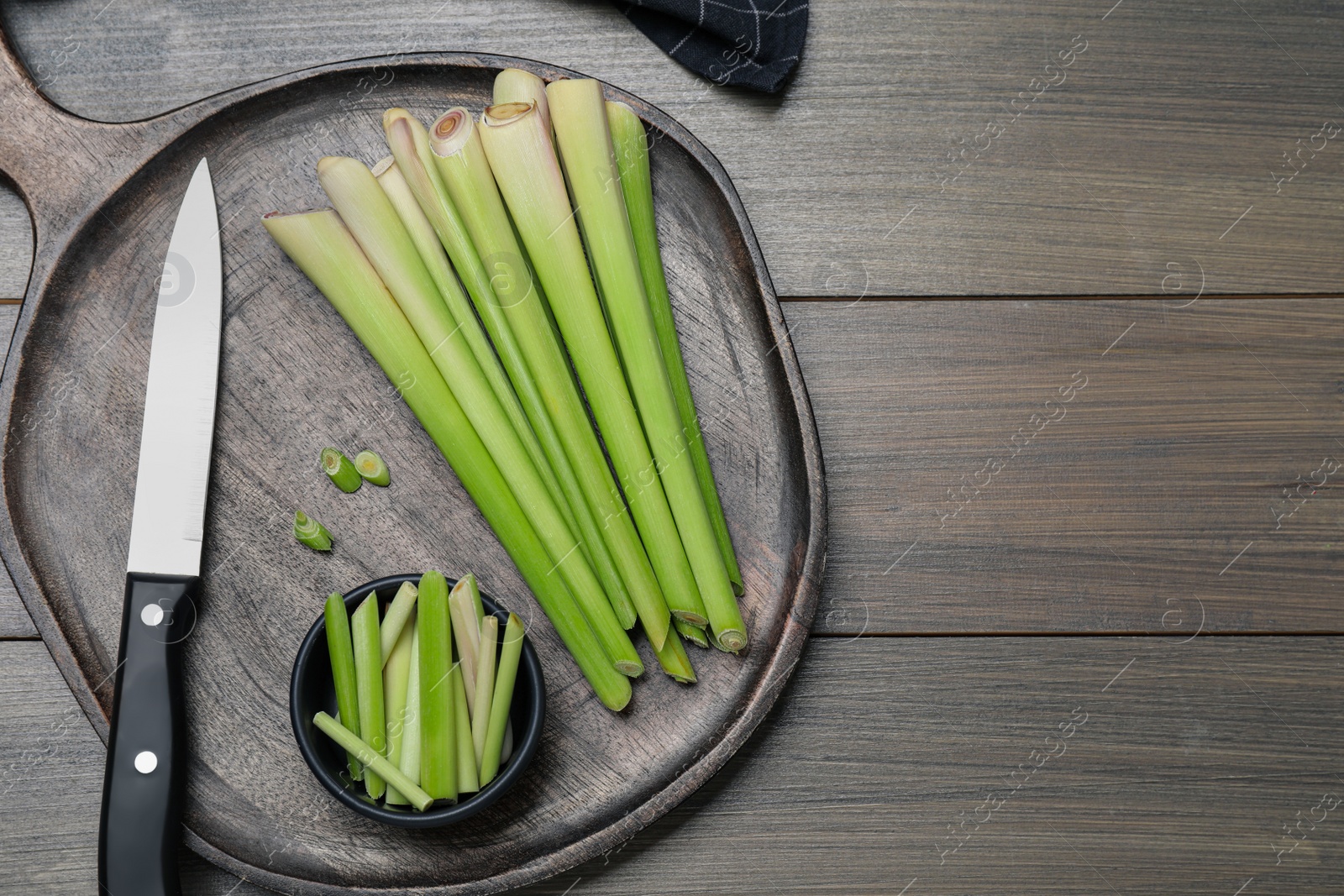 Photo of Fresh lemongrass, knife and cutting board on wooden table, flat lay. Space for text