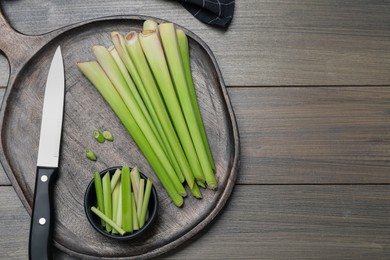 Fresh lemongrass, knife and cutting board on wooden table, flat lay. Space for text