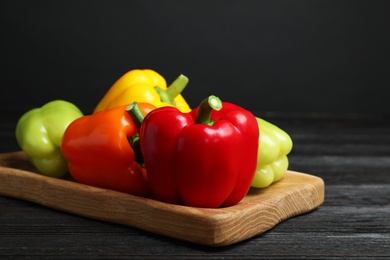 Board with ripe bell peppers on black wooden table