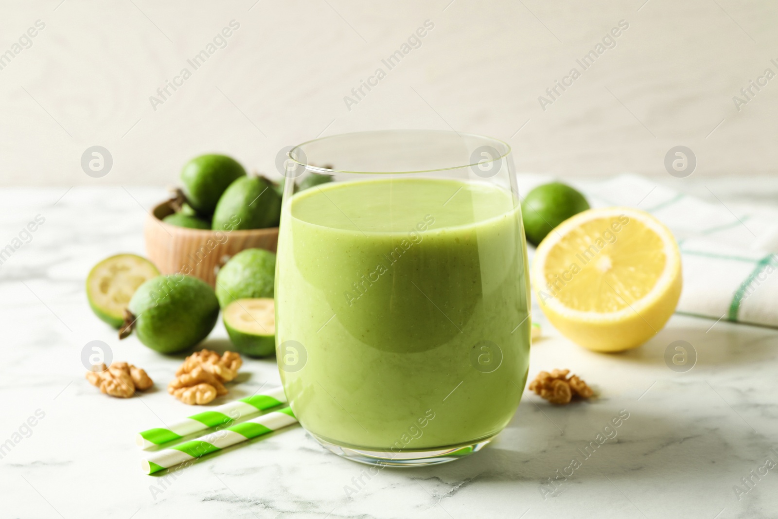 Photo of Fresh feijoa smoothie in glass on white marble table, closeup