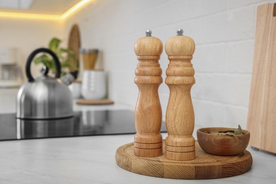 Photo of Wooden salt and pepper shakers, bowl with bay leaves on white countertop, space for text