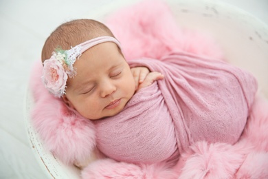 Adorable newborn girl lying in baby nest, closeup