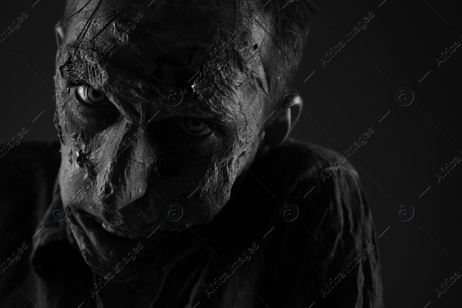 Photo of Scary zombie on dark background, black and white effect. Halloween monster