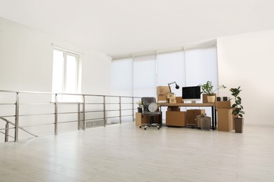 Photo of Cardboard boxes, computer and furniture in new office, space for text. Moving day