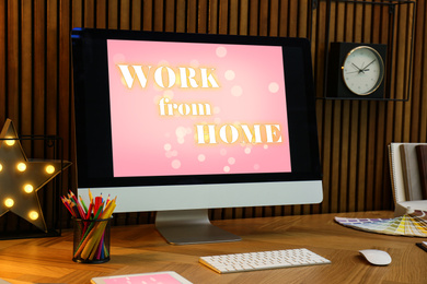 Image of Modern computer with text WORK FROM HOME on table in office 