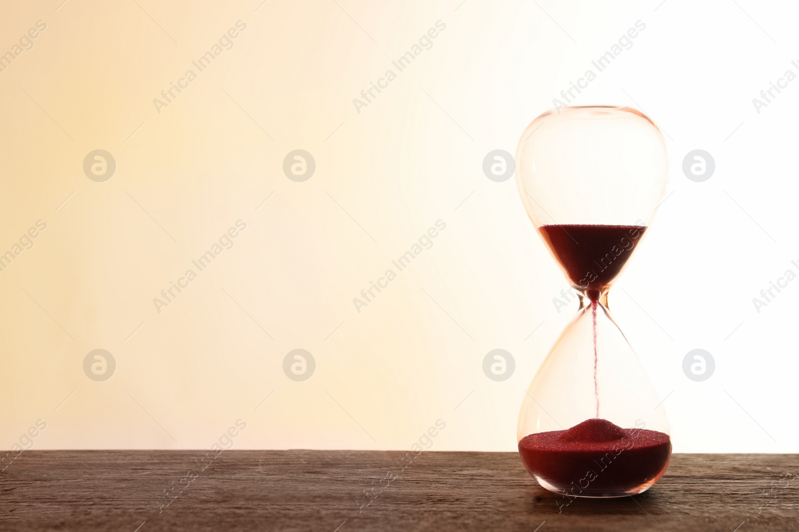 Photo of Hourglass with flowing sand on table against light background. Time management