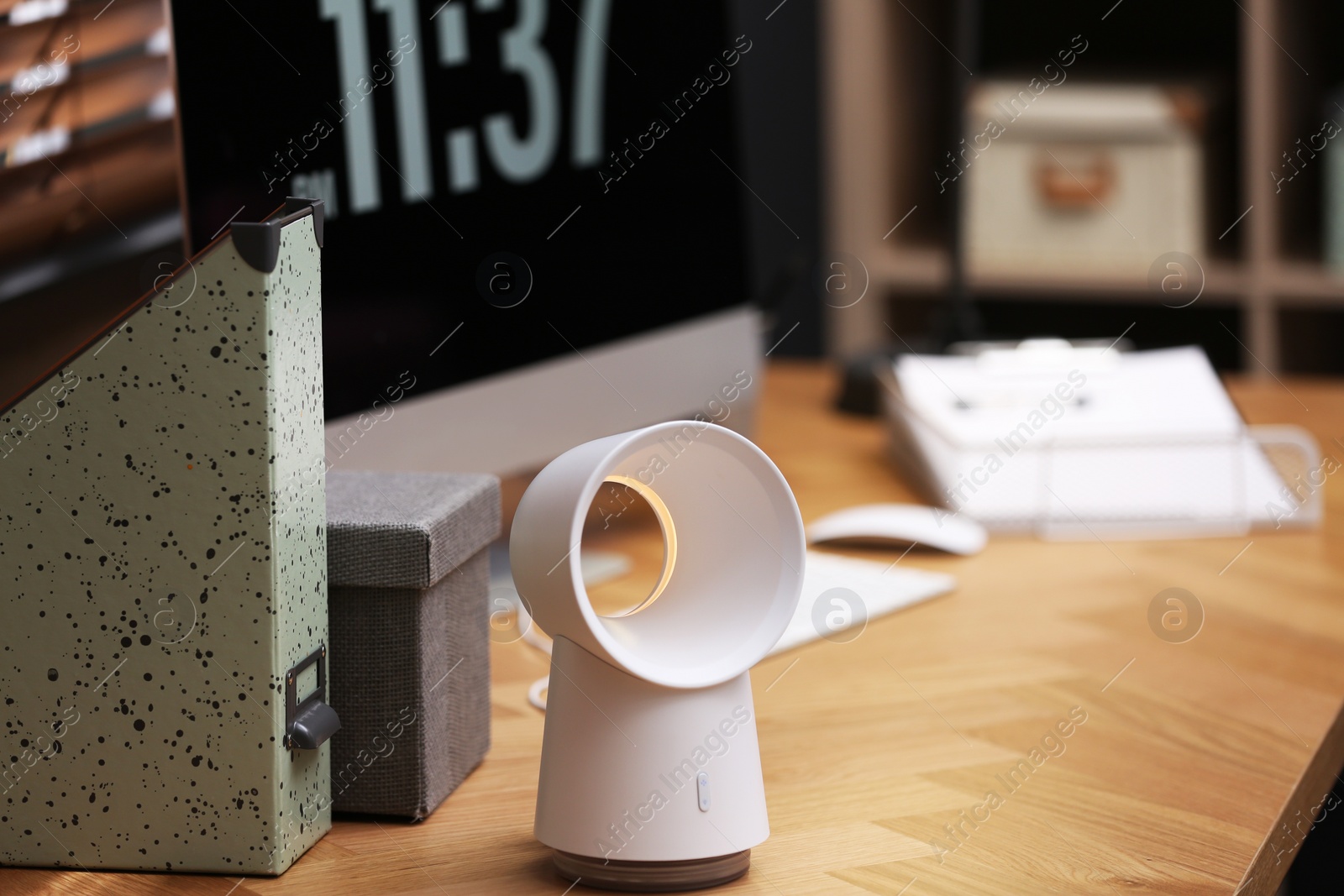 Photo of Modern electric fan on table in office. Space for text