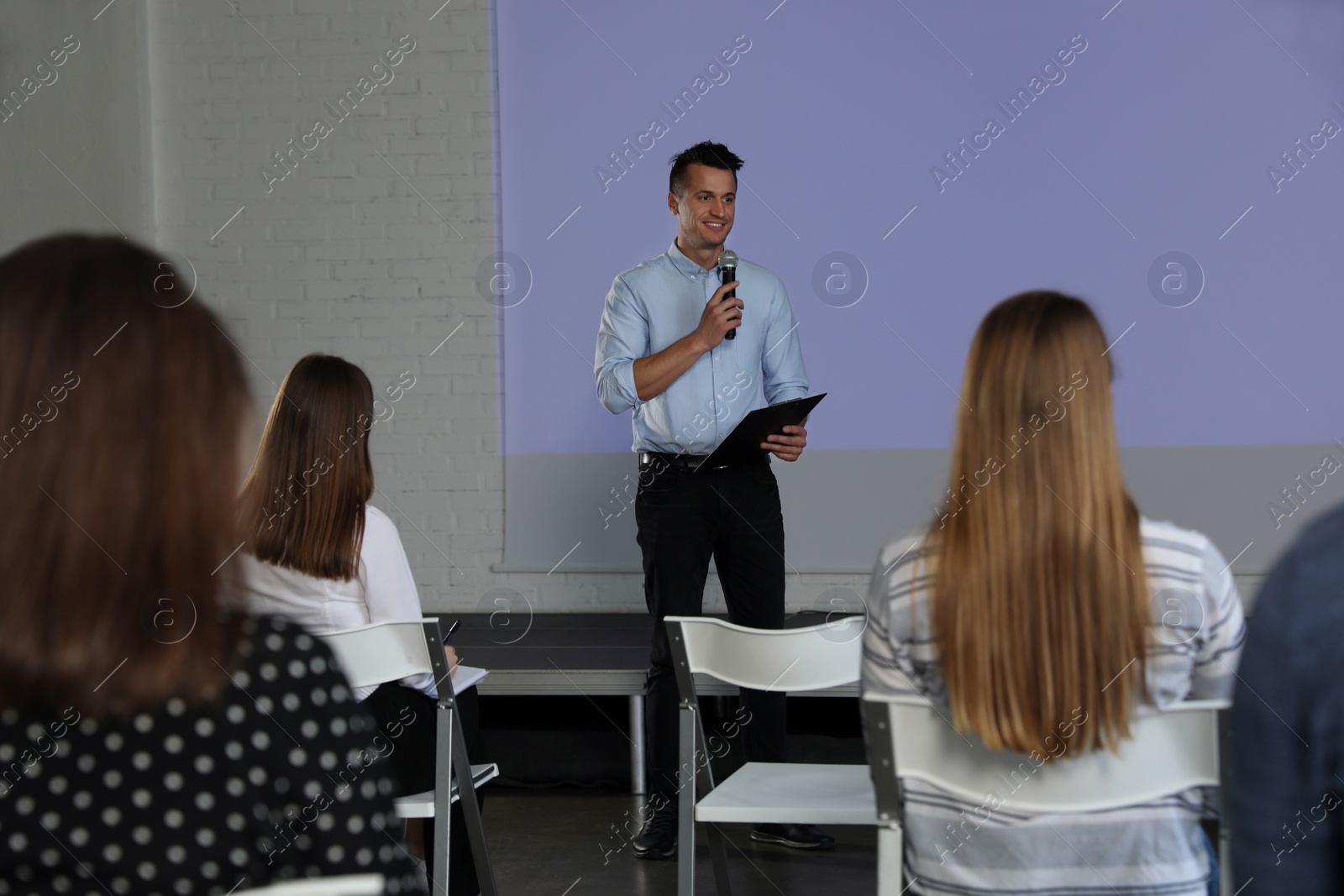 Photo of Male business trainer giving lecture in conference room with projection screen