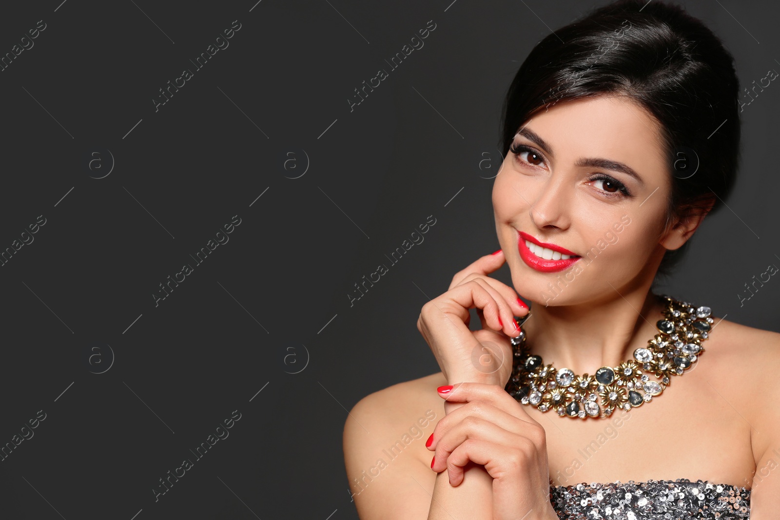 Photo of Beautiful young woman with elegant jewelry on dark background. Space for text