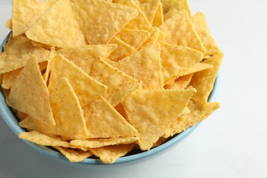 Photo of Tortilla chips (nachos) in bowl on white table, closeup