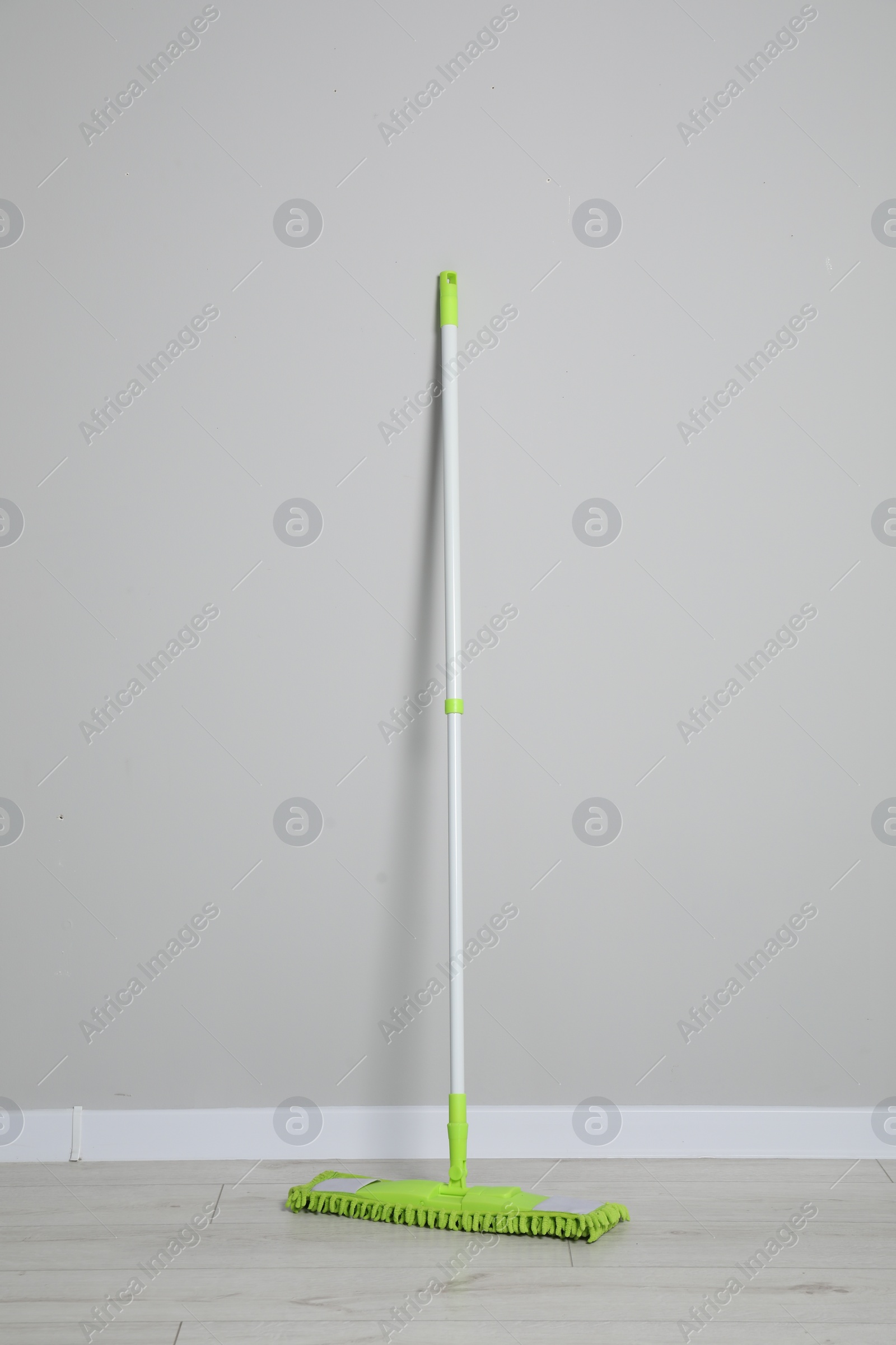 Photo of Mop with plastic handle near wall indoors