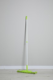 Mop with plastic handle near wall indoors
