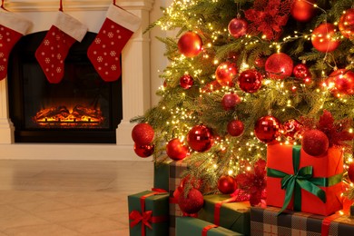 Many gift boxes under decorated Christmas tree and fireplace indoors