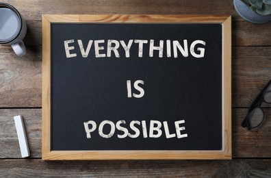 Image of Small chalkboard with motivational quote Everything is possible, coffee, chalk and glasses on wooden table, flat lay