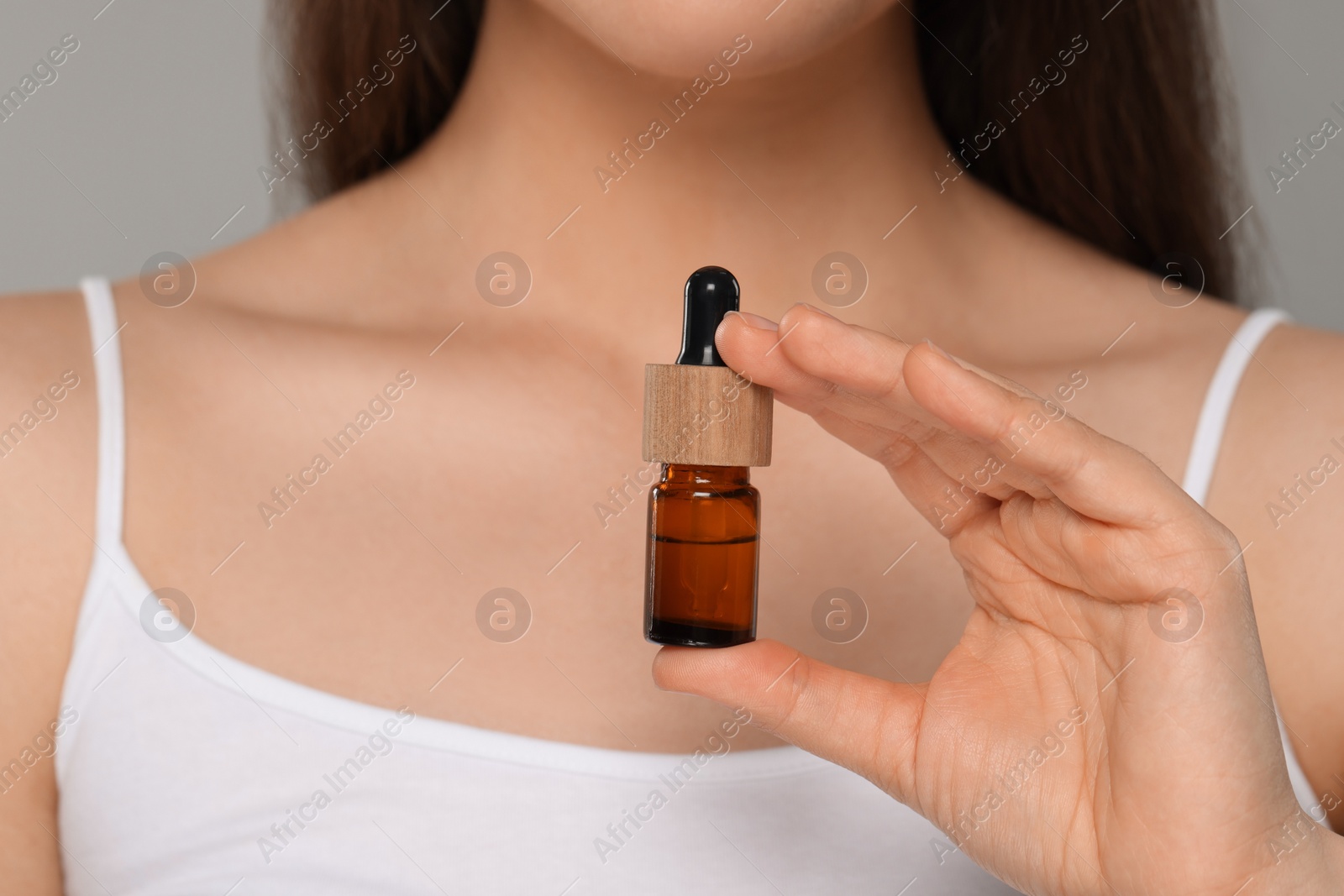 Photo of Woman holding bottle of essential oil, closeup