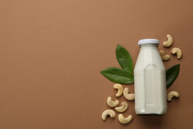 Photo of Vegan milk and cashew nuts on brown background, flat lay. Space for text