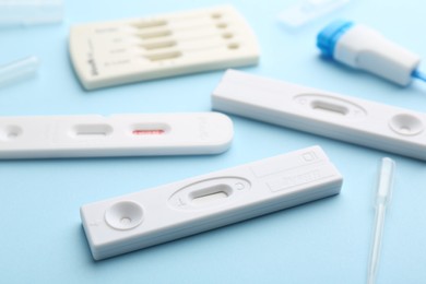 Photo of Different disposable express tests on light blue background