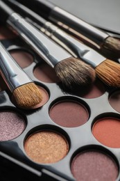 Photo of Beautiful eye shadow palette with brushes, closeup