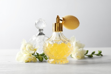Photo of Different perfume bottles and flowers on light background