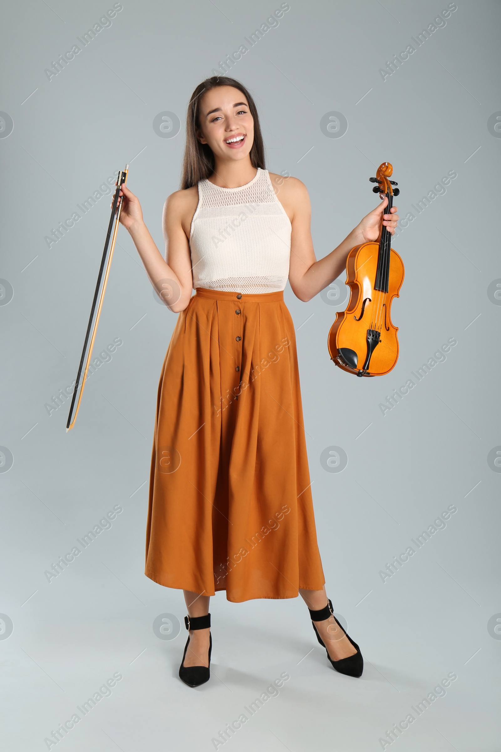 Photo of Beautiful woman with violin on grey background