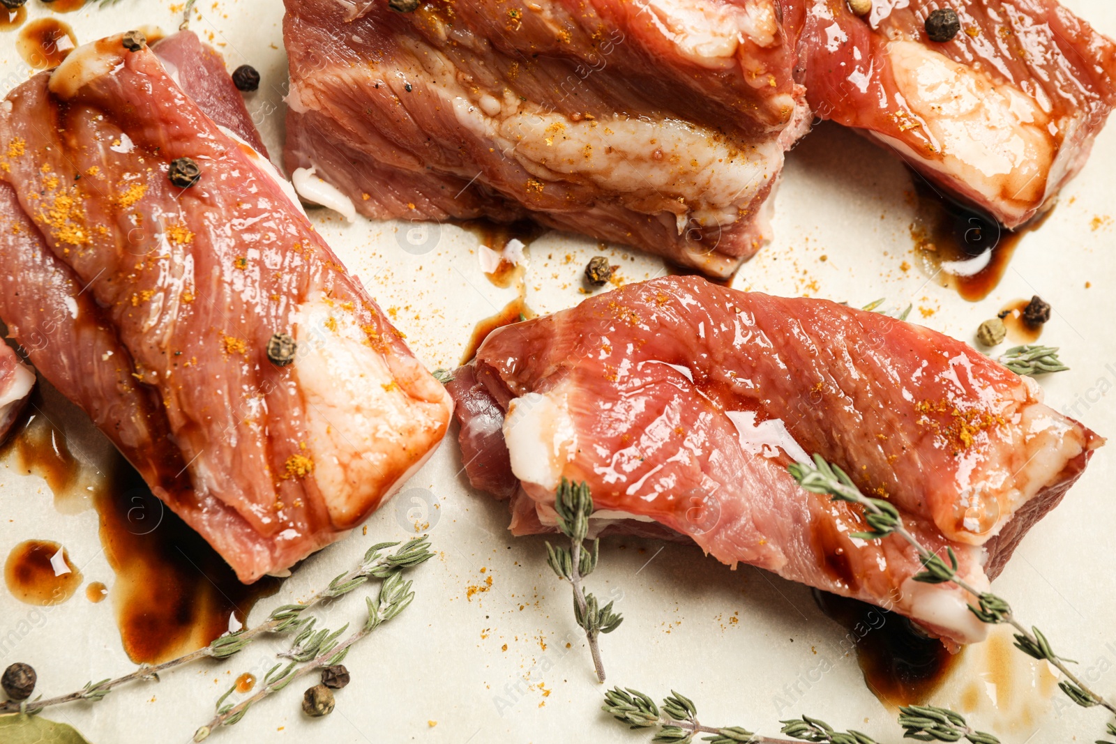 Photo of Raw marinated ribs with thyme and peppercorn, closeup