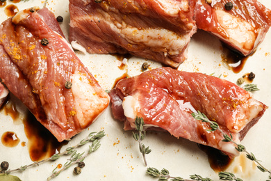 Photo of Raw marinated ribs with thyme and peppercorn, closeup