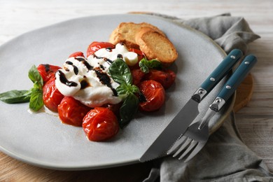 Photo of Delicious burrata cheese served with tomatoes, croutons and basil sauce on white wooden table, closeup