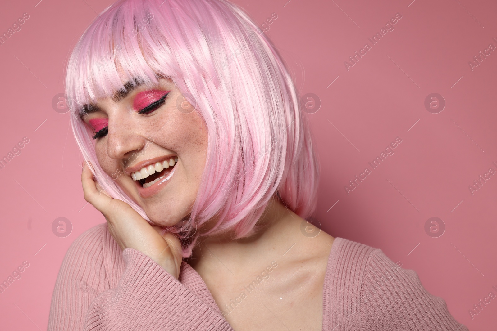 Photo of Happy woman with bright makeup and fake freckles on pink background, closeup