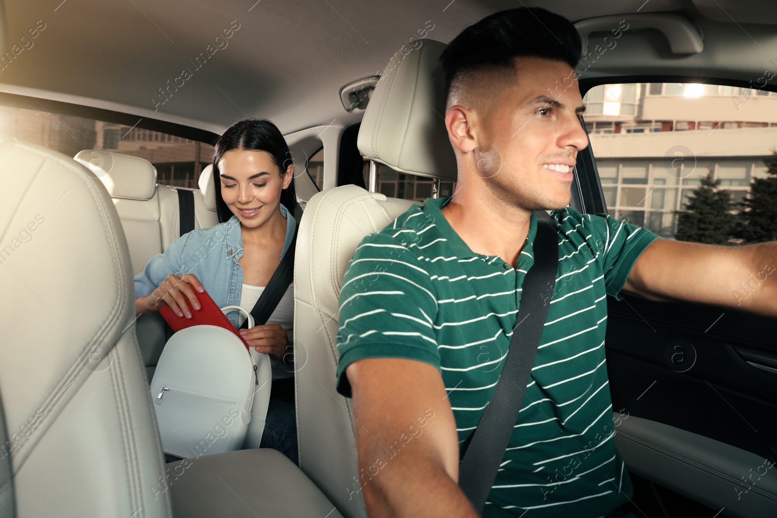 Photo of Young woman and taxi driver in modern car