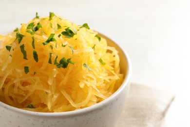 Bowl with cooked spaghetti squash on white background, closeup