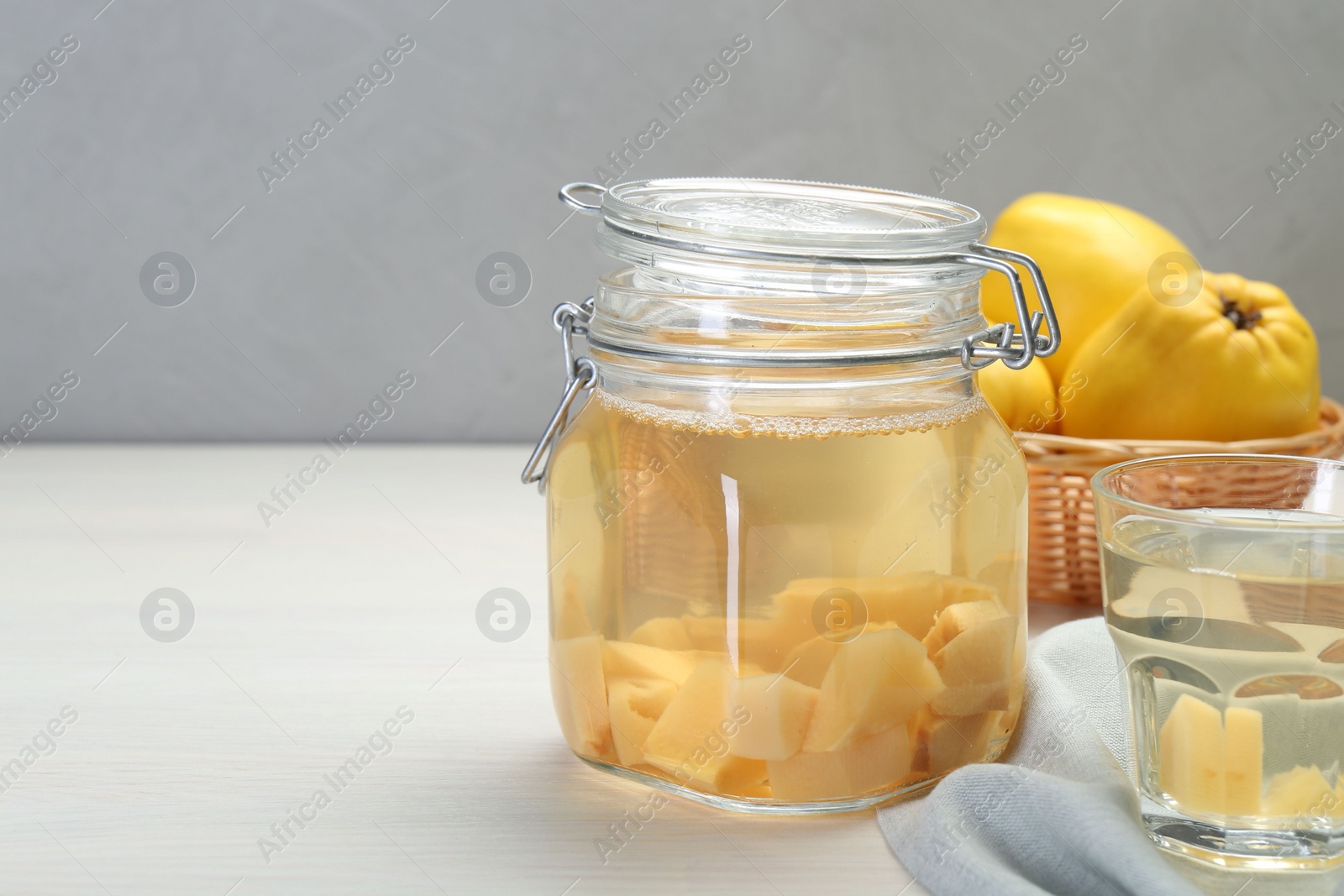 Photo of Delicious quince drink and fresh fruits on white wooden table, space for text