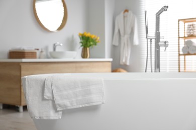 Photo of Fresh white towels on tub in bathroom. Space for text