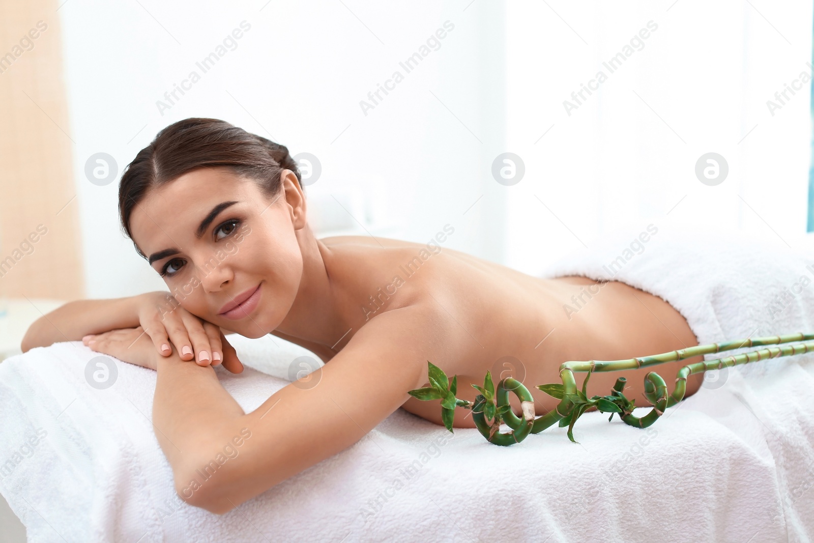 Photo of Beautiful young woman lying on massage table in spa salon