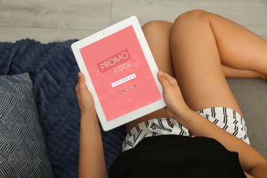 Woman holding tablet with activated promo code in online shopping app, top view