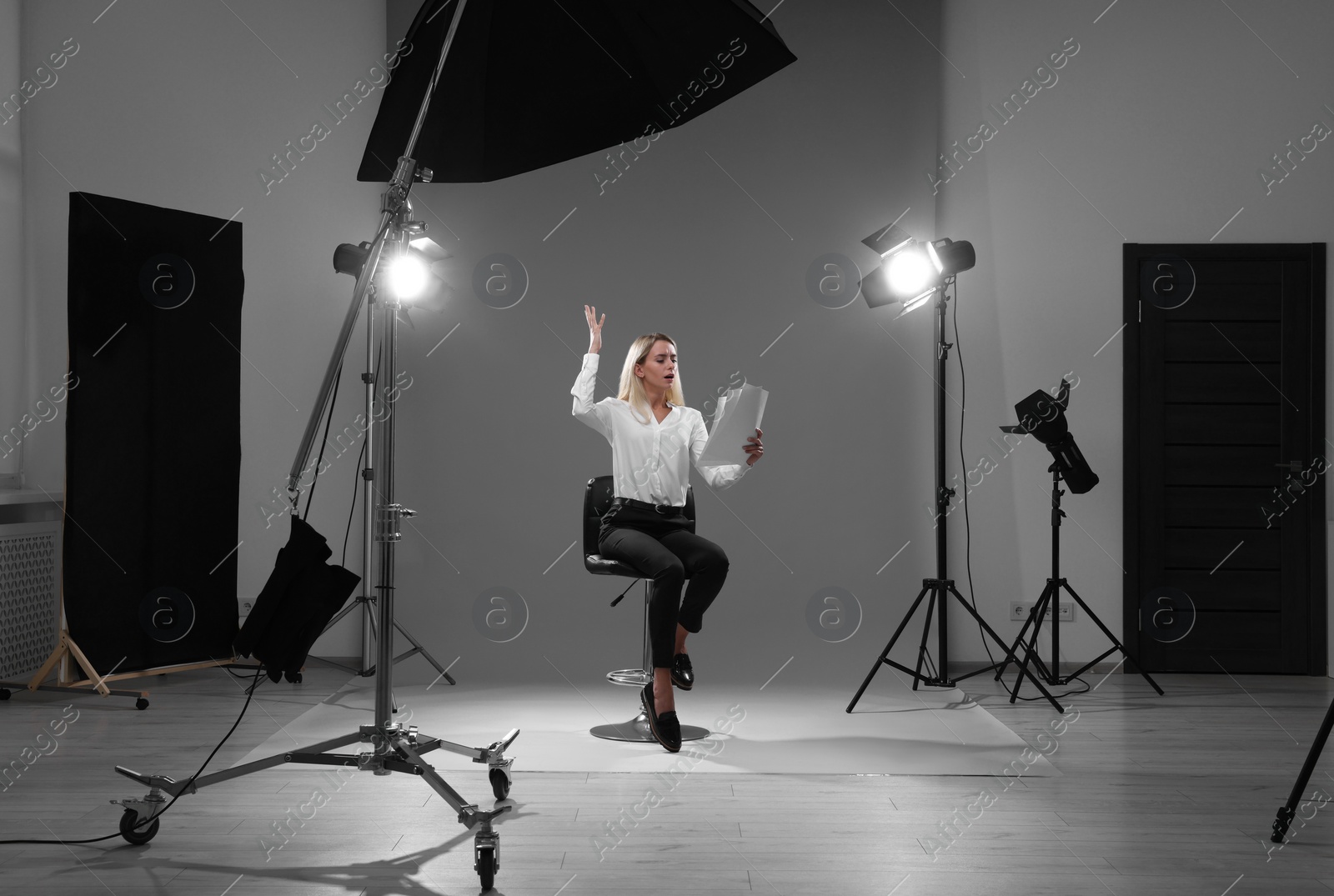 Photo of Casting call. Emotional woman with script performing against grey background in studio