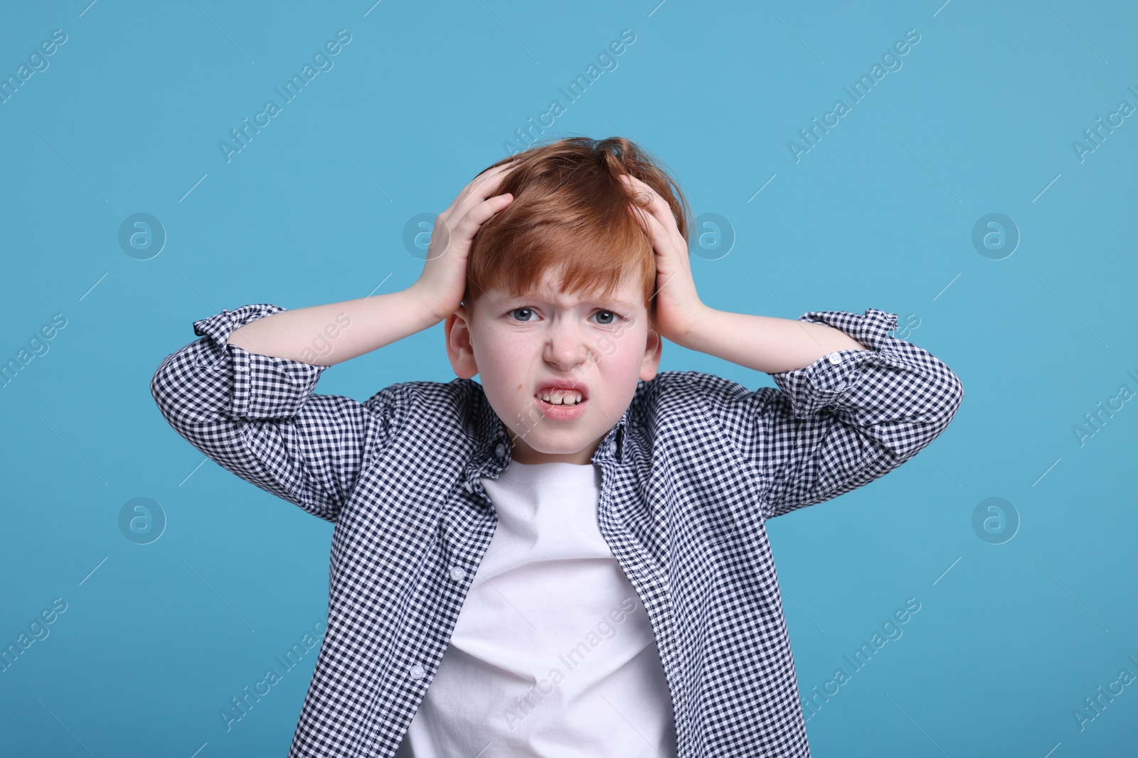 Photo of Surprised little boy on light blue background