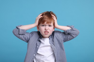 Photo of Surprised little boy on light blue background