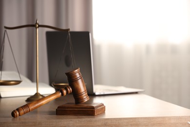 Photo of Law concept. Gavel, scales of justice and laptop on wooden table indoors, space for text