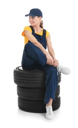 Female mechanic with car tires on white background