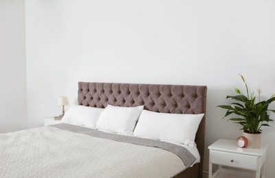 Photo of Large bed with blanket and pillows in modern apartment