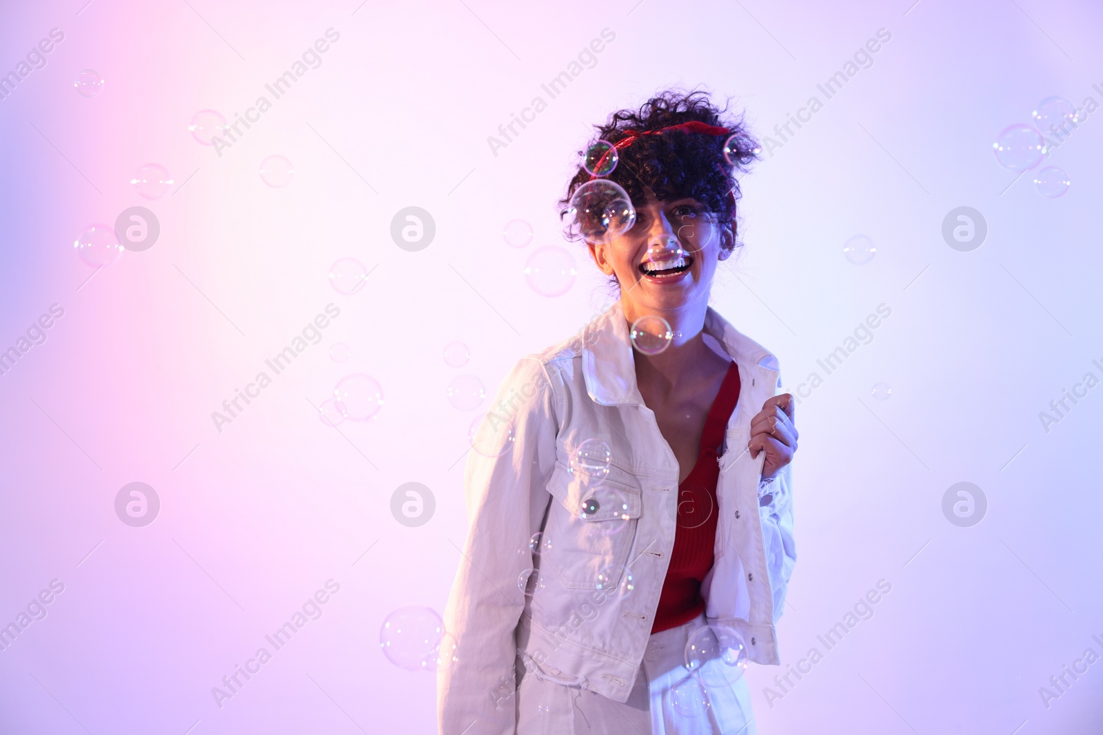 Photo of Beautiful young woman and bubbles on color background in neon lights. Space for text