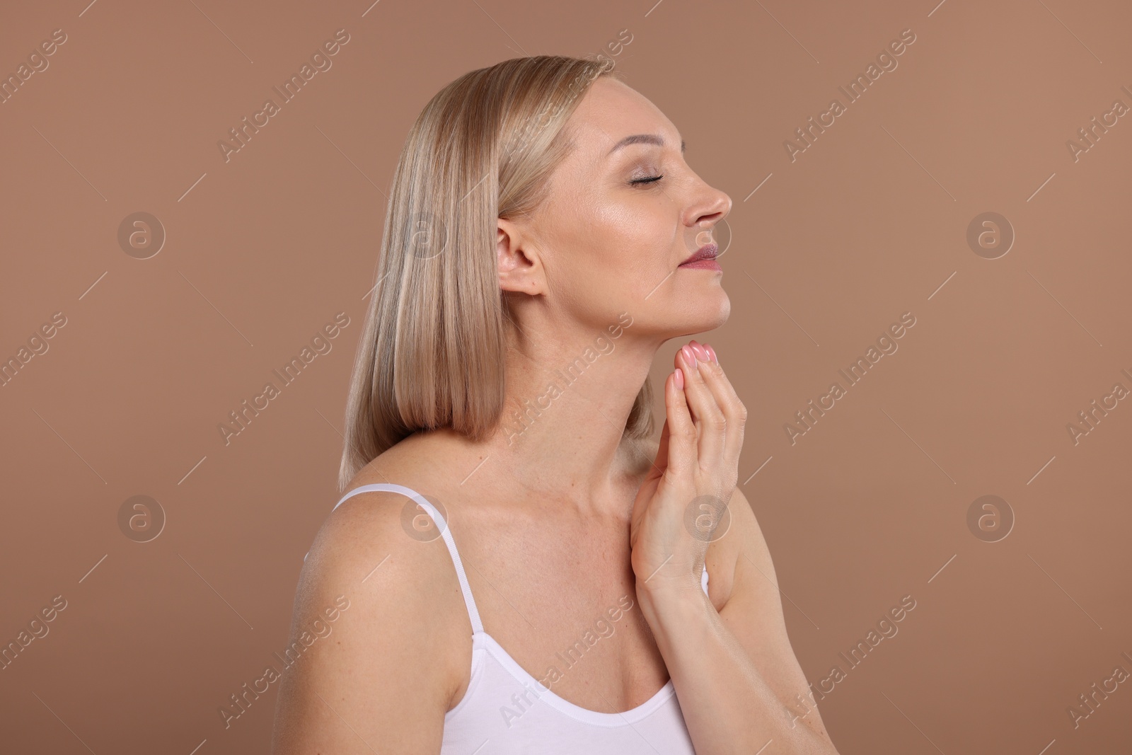 Photo of Beautiful woman touching her neck on beige background